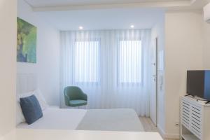 a white bedroom with a bed and a television at FAFEL LITTLE HOUSE - Quinta de Cravaz in Lamego