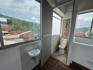 uma casa de banho com um WC, um lavatório e uma janela em Penthouse San Rafael em San Rafael