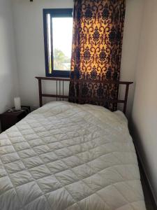 1 dormitorio con 1 cama blanca y ventana en Maison de 2 chambres avec vue sur la ville jardin clos et wifi a Saint Louis a 8 km de la plage, en Saint-Louis