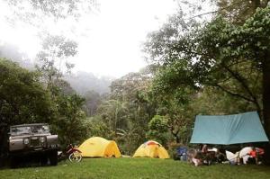 un grupo de personas acampando en un campo con tiendas de campaña en Exorcism Camp en Bukittinggi