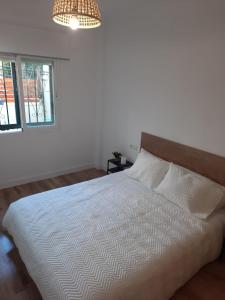 a white bed in a bedroom with a chandelier at Apartamento céntrico Benalmádena pueblo in Benalmádena