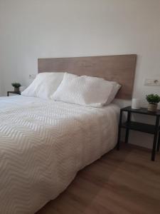 um quarto com uma cama branca e uma cabeceira em madeira em Apartamento céntrico Benalmádena pueblo em Benalmádena