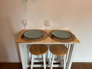 einem Holztisch mit zwei Gläsern und zwei Hockern in der Unterkunft Charmant studio Saint-Nazaire centre in Saint-Nazaire