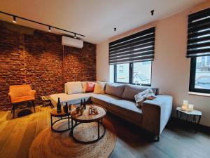 a living room with a couch and a brick wall at Un gîte sous roche in La-Roche-en-Ardenne
