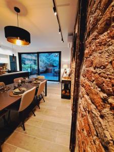 een eetkamer met een tafel en een bakstenen muur bij Un gîte sous roche in La-Roche-en-Ardenne