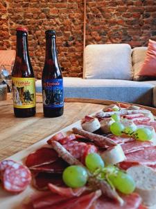 due bottiglie di birra e un piatto di cibo su un tavolo di Un gîte sous roche a La-Roche-en-Ardenne