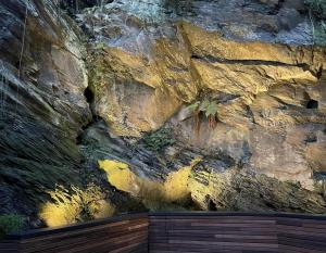 a rock wall with a wooden deck in front of it at Un gîte sous roche in La Roche-en-Ardenne