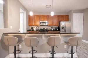 DISNEY PARKS- International Dr - Orlando Luxury Condominium- Fully Equipped - 3bed & 2 bath- في أورلاندو: مطبخ مع خزائن خشبية ومكتب مع كراسي بار