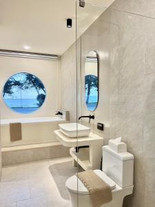 a bathroom with a sink and a toilet and two windows at Sunvada Beach Rayong in Rayong