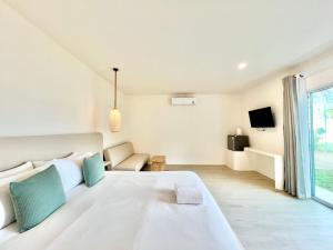 a white bedroom with a large bed and a window at Sunvada Beach Rayong in Rayong