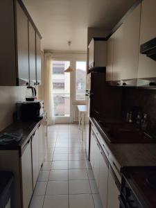 a kitchen with white cabinets and a large window at City Break - Room Chambre Geneva in Annemasse