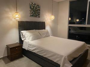 a bedroom with a bed with white sheets and a night stand at El Samario Cumbia Host-Playa Salguero- Santa Marta in Gaira