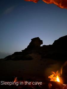 une photo d'un feu avec les mots dormant dans la grotte dans l'établissement Bedouin experiences, à Aqaba
