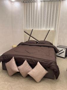 a bedroom with a large brown bed with four pillows at Asia Hotel Apartments in Irbid