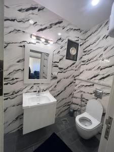 La salle de bains est pourvue d'un mur en pierre, de toilettes et d'un lavabo. dans l'établissement Asia Hotel Apartments, à Irbid