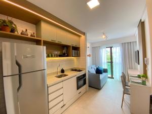 a kitchen with a refrigerator and a couch in it at Green Porto 207 -Flat premium no centro de Porto in Ipojuca