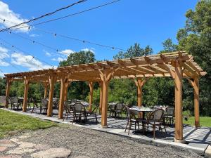 a wooden pergola with tables and chairs under it at The Alander in Copake