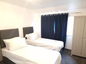 two beds in a room with blue curtains at Walker Lodge in Oldbury