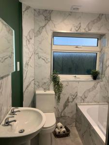 Un baño con lavabo, inodoro y ventana. en Tenby 2 bed flat with parking, plus pet, en Tenby
