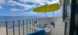 een tafel met een gele parasol op een balkon met uitzicht op de oceaan bij Résidence Pascal Paoli in Moriani Plage