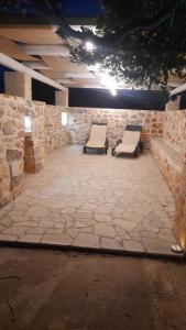 een patio met 2 stoelen en een stenen muur bij trullo madonna della grotta in Ceglie Messapica