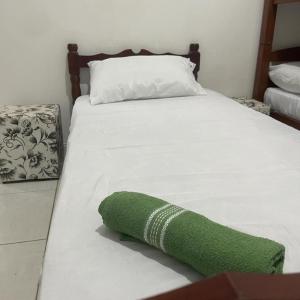 un letto bianco con un asciugamano verde sopra di 03 Doutor Hostel 800mts da praia a Guarujá