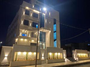 un palazzo alto con luci di fronte di notte di رويال جروب اربد Royal Group Hotel a Irbid