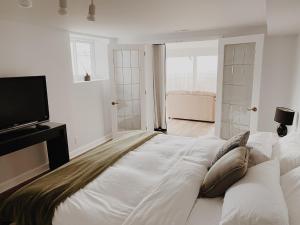 1 dormitorio blanco con 1 cama grande y TV de pantalla plana en Irish Mountain Suites, en Meaford