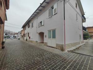 - un bâtiment blanc dans une rue pavée dans l'établissement Dante alighieri, à Villa Colle Onorato