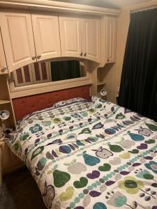 a bed with a flowered comforter in a bedroom at CW27 St Osyth Holiday Park with disability Ramp in Saint Osyth