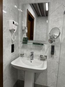 a bathroom with a white sink and a mirror at Mir Luxe Plaza in Tashkent
