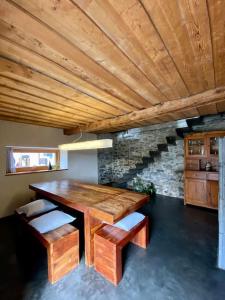 uma sala de jantar com uma mesa de madeira e bancos em Maison Alphonse de Mélie, avec cachet. em Conthey