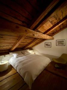 a bedroom with a white bed in an attic at Maison Alphonse de Mélie, avec cachet. in Conthey