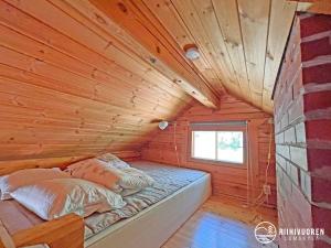 a bed in a log cabin with a window at Kalaranta Cottage in Muurame