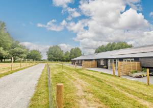 a barn with a dirt road next to a building at Roosters Rest in Beccles