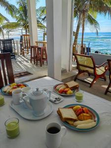 una mesa con un desayuno de tostadas y café y el océano en SEASHORE Resort & Villa, en Talpe