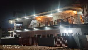 uma casa com varanda à noite com luzes em Jeru Homes em Ooty