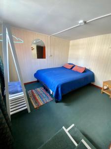 Un dormitorio con una cama azul y una escalera en La Minga Hostel en Castro