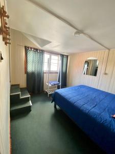 Un dormitorio con una cama azul y algunas escaleras en La Minga Hostel en Castro