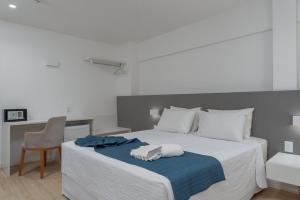 um quarto com uma cama com um cobertor azul e uma cadeira em Hotel Praia Bonita Jangadeiros Pajuçara em Maceió