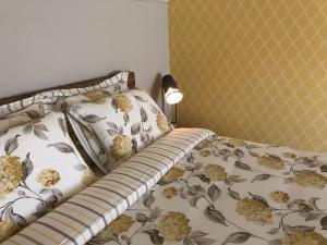 1 dormitorio con 1 cama con colcha de flores y lámpara en Vakantiewoning Hof7tien90, en Nuth