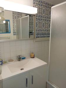 une salle de bains blanche avec un lavabo et un miroir dans l'établissement Le Bellevue YourHostHelper, à Gruissan