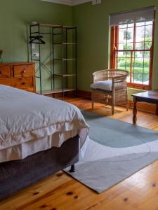 a bedroom with a bed and a chair and a window at Charming Heritage Villa Tamboerskloof in Cape Town