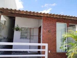 a brick house with a white fence in front of it at Casa privativa no norte da ilha in Florianópolis