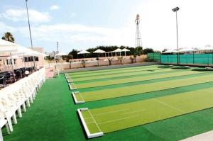 a tennis court with green turf and white chairs at Kama Lifestyle Apartments in Protaras
