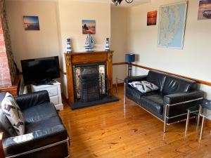 a living room with two leather couches and a fireplace at Lovely apartment overlooking the harbour and bay in Ardglass