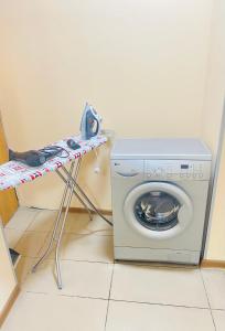 a washing machine sitting next to a table next to a washer at Like Home Rooms in Almaty