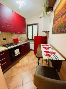 een keuken met rode kasten en een tafel met een tafel sidx sidx sidx bij La maison de Daniela in Settimo Vittone