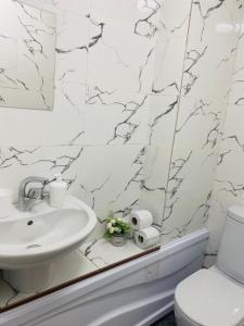 La salle de bains blanche est pourvue d'un lavabo et de toilettes. dans l'établissement Like Home Rooms, à Almaty