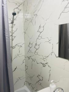 a bathroom with a white marble shower curtain at Like Home Rooms in Almaty